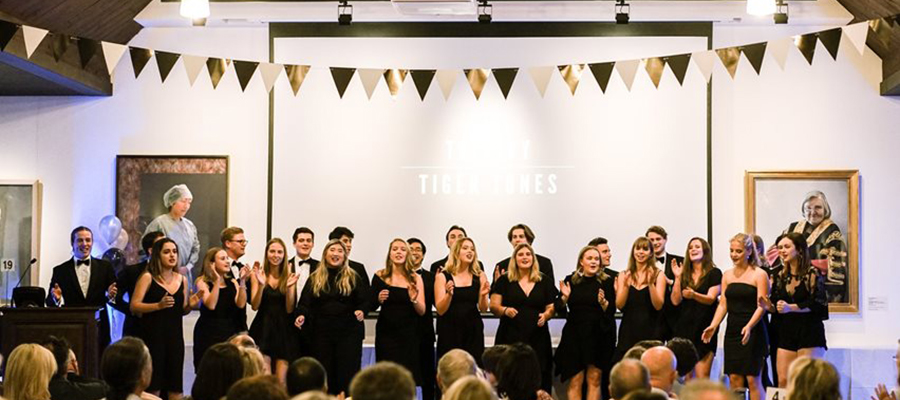 A group of Trinity's a capella groups, the Tiger Tones and the Candystripes performing on the stage in front of the audience